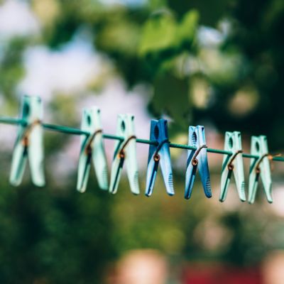 Fünf grüne und zwei blaue Wäscheklammen hängen an der Wäscheleine.