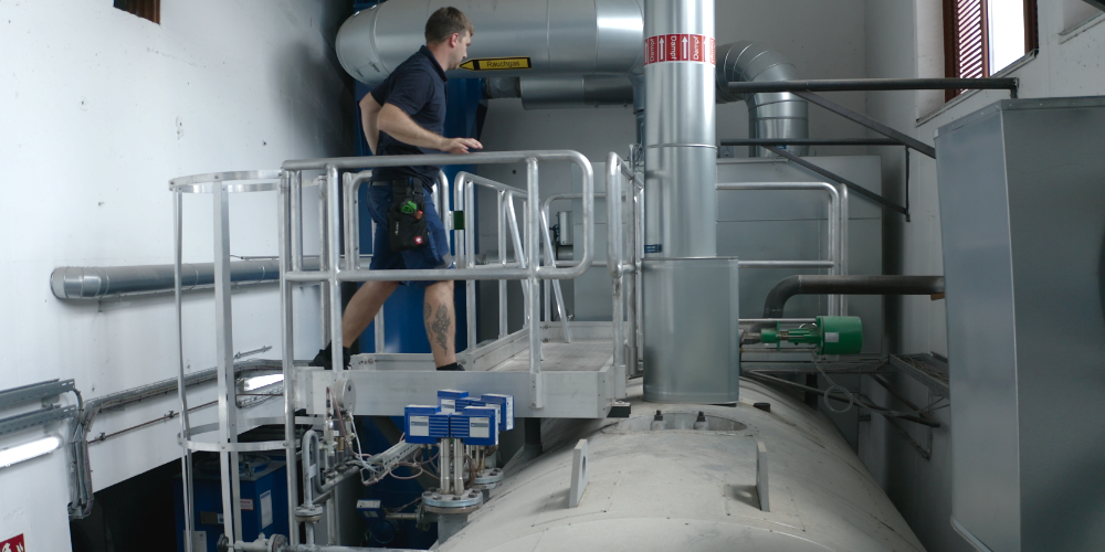 Techniker macht auf einem höheren Laufweg oberhalb des Dampfkessels Servicearbeiten