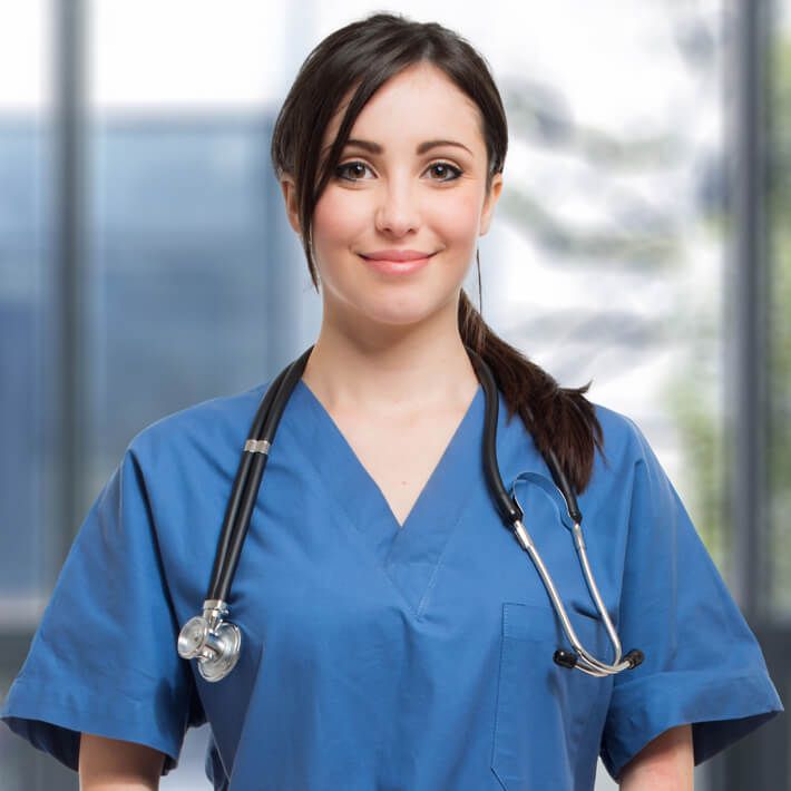 Weibliche Pflegekraft im blauen Kasack und Stethoskop um den Hals